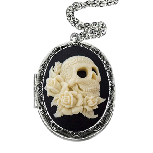A silver locket with a carved white skull design and a floral arrangement on a black background.