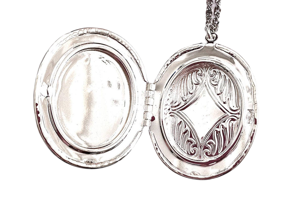 An open silver locket with an oval-shaped compartment and a decorative metal design on the front.